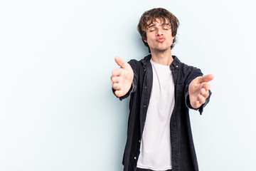 Poster - Young caucasian man isolated on blue background folding lips and holding palms to send air kiss.