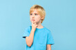 Young pensive boy, trying to find solution to a problem, studio portrait isolated on pastel blue background.