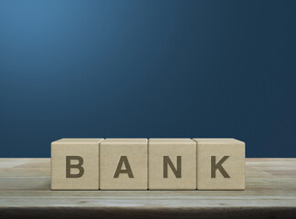 Poster - Bank letter on wood block cubes on wooden table over light blue wall, Business banking service concept