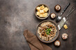 Risotto with mushrooms in a bowl and ingredients on a dark brown grunge background. Top view, flat lay, copy space.