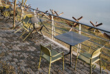Fototapeta Konie - Empty tables and plastic chairs on the summer terrace near a small cafe. Cafeteria furniture outside