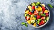 Healthy fresh fruit salad in a bowl on a gray background