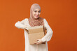 Beautiful overjoyed young smiling muslim woman in traditional religious hijab  holding an open cardboard box.