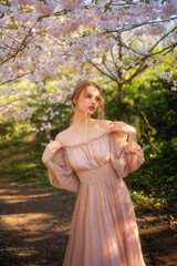 Beautiful  girl in pink  vintage dress  standing near colorful flowers. Art work of romantic woman .Pretty tenderness model posing with emotions.