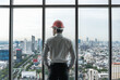 © Jack Tamrong - Back view engineer man standing and looking out of high rise office windows