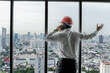 © Jack Tamrong - Back view engineer man standing and looking out of high rise office windows