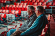 Two fans watching sporting event in empty stadium