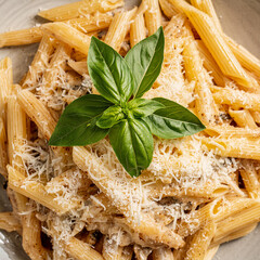 Wall Mural - Close up penne pasta in tomatoes, cheese and green basil. Classic Italian pasta dish