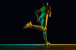 Wellness. Yung sportive woman in sportswear and headphones in motion, running on black background in neon light. Concept of active and healthy lifestyle, sport, hobby, motivation, endurance