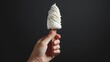 Captivating advertisement shot of a hand gripping a frozen vanilla dessert on a stick, contrasted on a minimalist black background, studio lighting