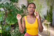 Satisfied African American girl talking on cellphone with interest surrounded by houseplants. Pleased black female gardener calls on smartphone while taking break from work to care for indoor plants.