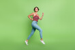 © deagreez - Full length photo of good mood cheerful girl wear stylish clothes running jogging going empty space isolated on green color background