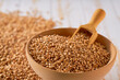 Raw organic wheats are scattered in a wooden bowl close up.