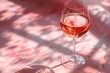 A glass of pink wine on a pink background.