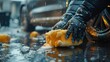 closeup male hands in rubber gloves of a car wash worker polishing a car body with sponge