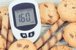 Glucose meter with high sugar level and cookies. Healthy nutrition and reduction eating sweets during diabetes