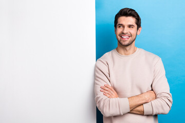 Poster - Photo of pleasant man with stylish haircut dressed beige sweatshirt arms folded look at sale empty space isolated on blue color background