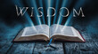 © ana - The book of Wisdom. Open bible with blue glowing rays of light. On a wood surface and dark background. Related to this book: Righteousness, Knowledge, Virtue, Immortality, Justice, Understanding