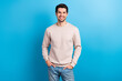 © deagreez - Portrait of funny satisfied man with brunet hairstyle dressed beige sweatshirt standing arms in pockets isolated on blue color background