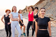 Group of adult fit multiethnic women in sportswear posing at wild coast. Concept of wellness and female friendship