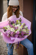 Look down girl in warm knitted hat with a chic bouquet of lilac bushes