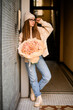 Beautiful girl in beige sports shoes standing near a wall with a chic roses