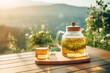 A cup with teapot of hot herbal tea sits on a wooden table, steam rising from the fresh brew, offering a comforting refreshment against a natural backdrop.