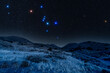Starry nightscape with the Orion constellation glowing over a mountainside