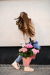 Turned around girl in a hat and jeans with pink and blue bouquets in the hands