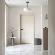 Modern minimalist entrance hall interior with a dry branch in a vase on a round decorative table on one side of the front door and a gray round ottoman on the other side, an oval pendant lamp.
