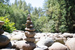 Rock pile or rock stack in front of defocused forest on a sunny day. Pebble tower or rock pyramid. Concept for relaxing, zen, spiritual or yoga. Nature background. Selective focus. North Vancouver BC