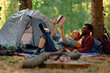 Young happy couple reading  novel on camping in forest.