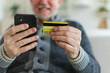Senior man shopping online holding smartphone paying with credit card. Old grandfather buying on Internet enter credit card details. Online shopping delivery service Older generation modern tech usage