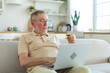 Senior man shopping online using laptop paying with credit card. Old grandfather buying on Internet enter credit card details. Online shopping delivery service. Older generation modern tech usage