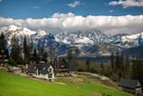 Fototapeta  - Wiosenna panorama na Tatry Wysokie z góralskimi domami w widokowym miejscu na pierwszym planie