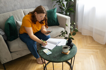 The 30s woman considers the costs of gas, electricity, heating. The concept of increasing tariffs for services. Woman with financial bills calculating on smart phone. Debt, bankruptcy