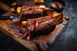 Traditional barbecue burnt chuck beef ribs marinated with spicy rub and served as close-up on an old rustic wooden board with knife 