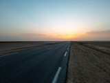 Fototapeta Niebo - Beautiful colourful sunset over endless empty road in middle of desert. Asphalt highway in Tunisia, North Africa.	