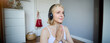 Close up portrait of young relaxed woman in headphones, holding hands together in namaste gesture, listening to meditation podcast, practice yoga