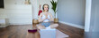 Portrait of blond young woman meditating, practise yoga, using yoga podcast to workout at home, sits on rubber mat