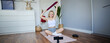 Image of smiling, athletic fitness instructor, female social media influencer, recording video about workout, showing how to use resistance bands on digital camera, sitting on rubber yoga mat at home