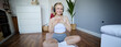 Image of sporty young woman doing workout at home, using rubber yoga mat, listening to music and exercising