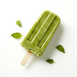 Green popsicle on a white background with a few mint leaves scattered around it.