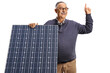 Mature man behind a solar panel smiling and pointing up
