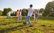 © Studio Romantic - Happy children boys and girls running towards ball playing together in the park on the green grass on a summer holidays. Teenage kids in casual clothes playing football in nature in camp.