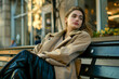 A woman lounges on a city bench, her casual attire blending seamlessly with the everyday scene.