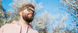 Banner Cool handsome millennial man side face looking away portrait in blooming springtime trees. Blur sakura blossom spring tree background. Copy space