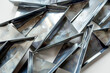 A pile of metal pieces with a triangular shape. The metal pieces are scattered and overlapping each other. Concept of chaos and disorder, as the pieces are not arranged in a neat or organized manner