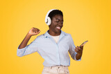 Fototapeta  - Joyful woman with headphones dancing to music isolated