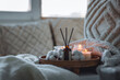 Cozy corner for home meditation, relaxation, detention. Aroma reed diffuser, aromatic burning candles. Concept of wellbeing, wellness, pleasure, aromatherapy. Apartment room decor, house design